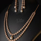Pearl earring on a black stand against a dark green background